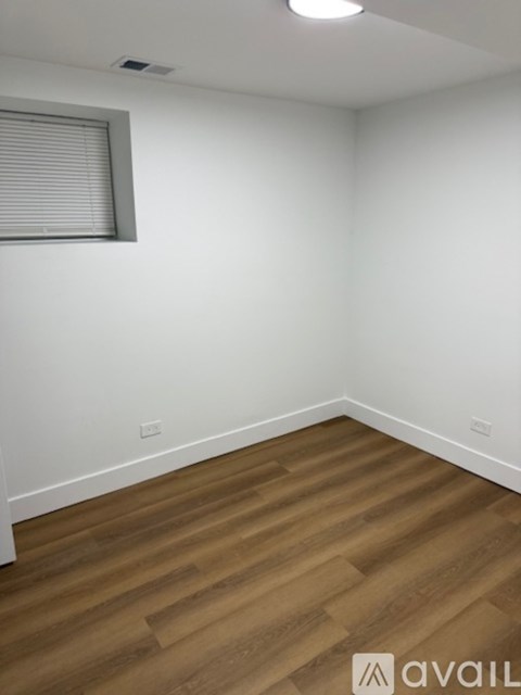 A room with wooden flooring and a window with blinds.