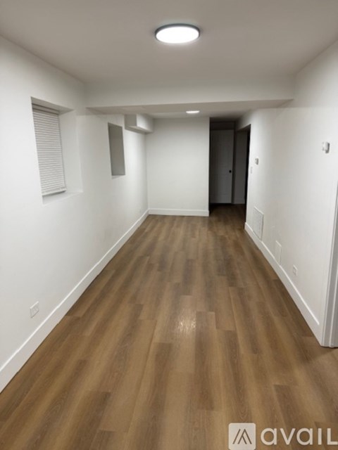 A long hallway with wooden floors and white walls.