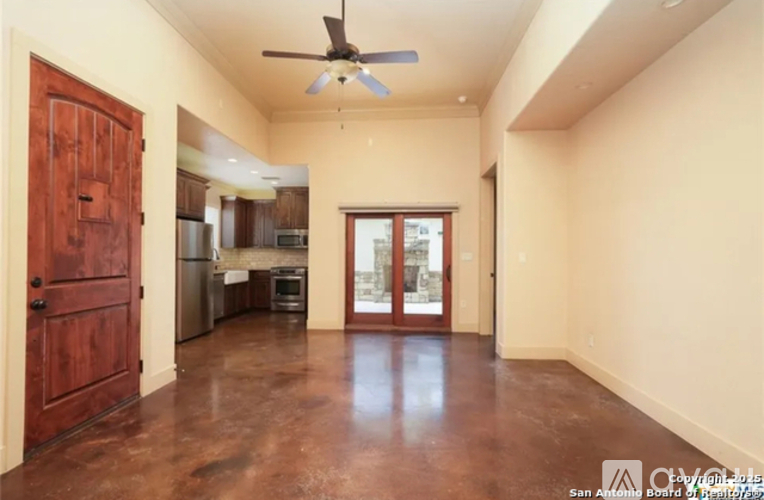 A room with a ceiling fan and brown flooring.