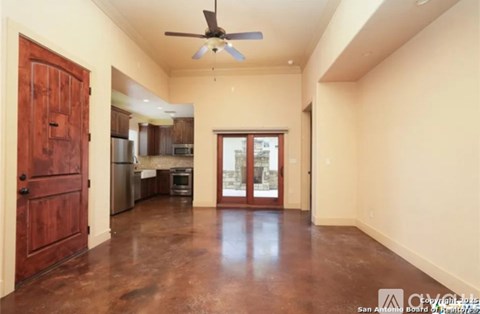 A room with a ceiling fan and brown flooring.