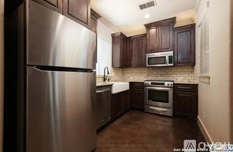 A kitchen with a stainless steel refrigerator and brown cabinets.