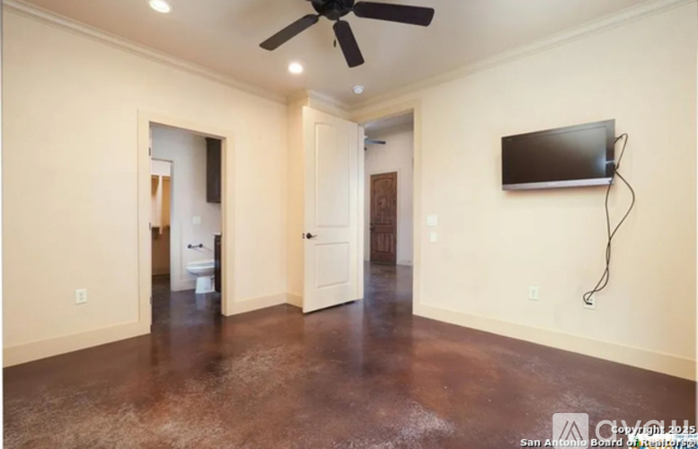 A room with a ceiling fan and a flat screen TV mounted on the wall.
