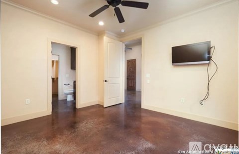 A room with a ceiling fan and a flat screen TV mounted on the wall.