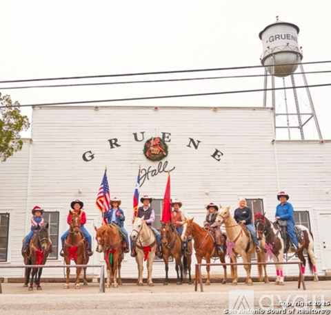 A group of people riding horses in front of a building with the word Gruene on it.