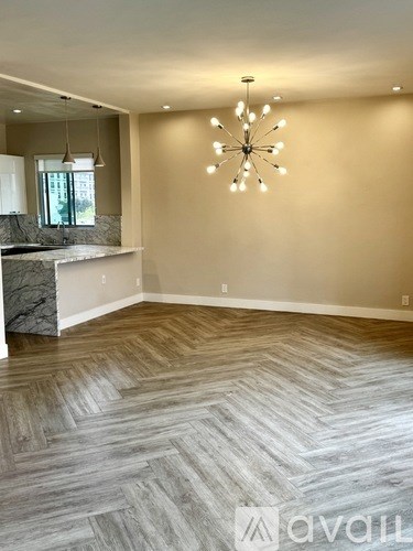 A spacious room with a marble island and a herringbone patterned floor.