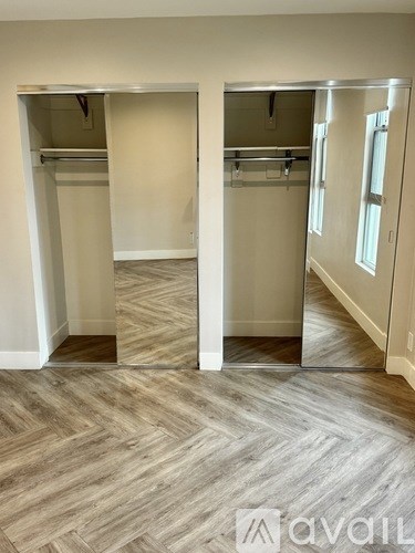 A room with a wooden floor and a wall with a mirror.