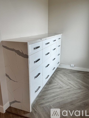 A white cabinet with drawers is in a room with a wooden floor.