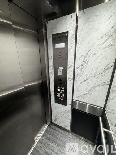 A stainless steel elevator with a control panel and a marble wall.