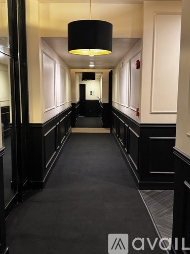 A long hallway with black trim and a black carpet.