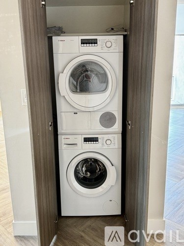 A white front loading washing machine is in a cabinet.