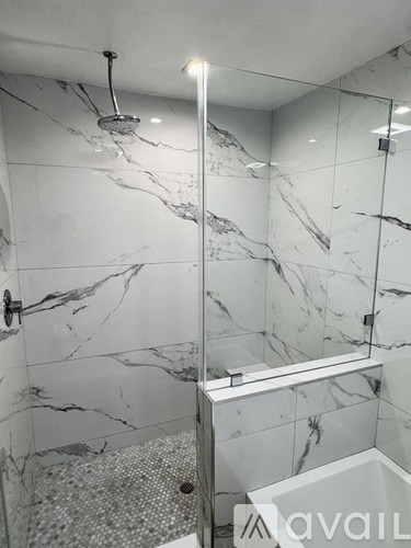 A bathroom with marble tiles and a glass shower enclosure.