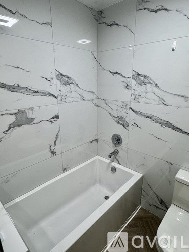 A bathroom with marble tiles and a white bathtub.