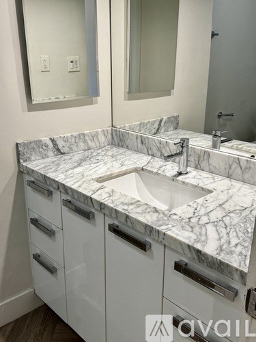 A bathroom with a marble countertop and white cabinets.