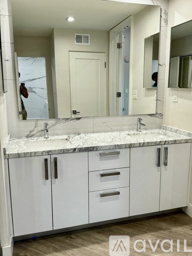 A bathroom with a marble countertop and white cabinets.