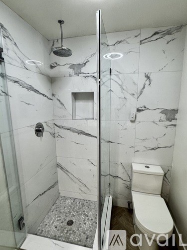 A bathroom with marble tiles and a walk-in shower.