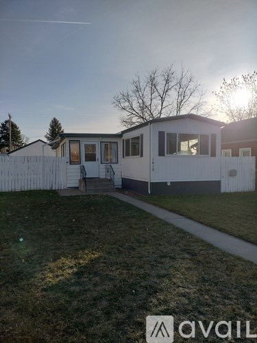 A white mobile home with a brown door and a white picket fence.