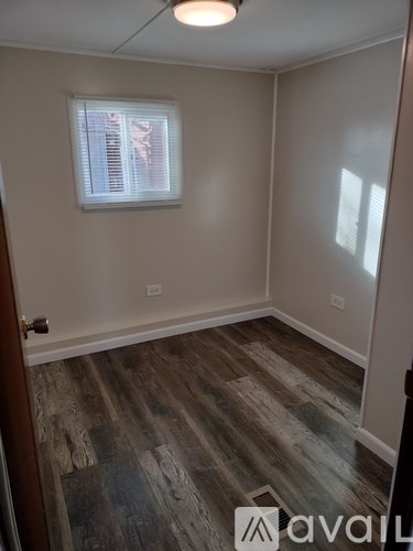 A room with wooden flooring and a window with blinds.