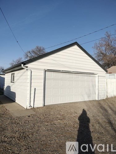 A two-car garage with a white door and a shadow of a person in front of it.