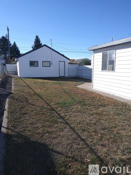 A backyard with a white house and a white fence.