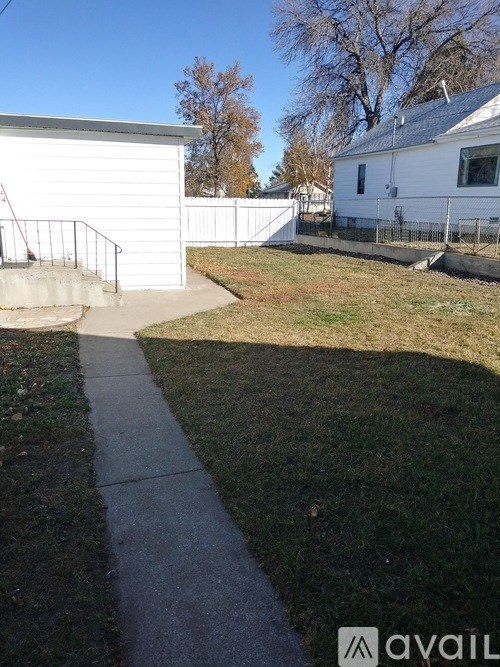 A white house with a grey roof and a white fence.