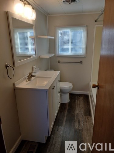 A bathroom with a sink, toilet and mirror.
