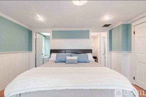 A bedroom with a large bed and a white headboard.