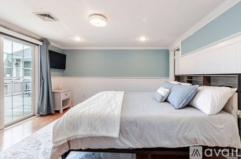 A bedroom with a large bed and a flat screen TV mounted on the wall.
