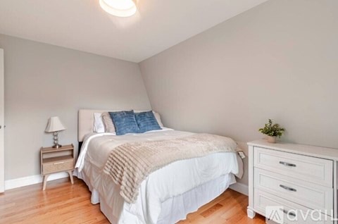 A bedroom with a bed, nightstand, and lamp.