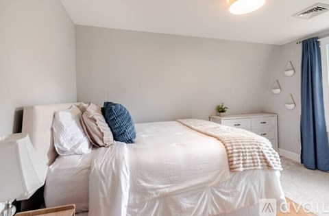 A bedroom with a white bed and a blue pillow.