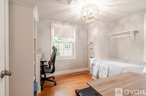 A bedroom with a bed, desk, and chair.