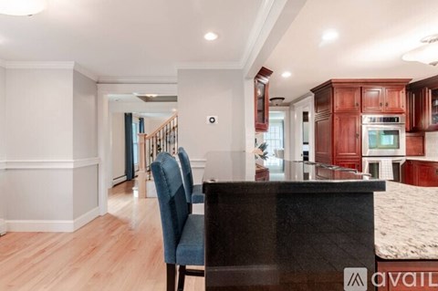 A kitchen with a black countertop and a blue chair.