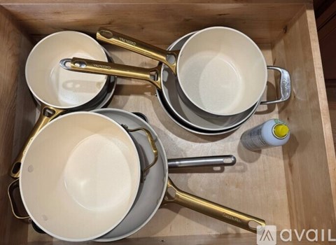 A drawer with pots and pans and a bottle of cleaner.