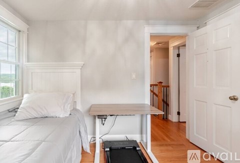 A bedroom with a bed, a table, and a door.