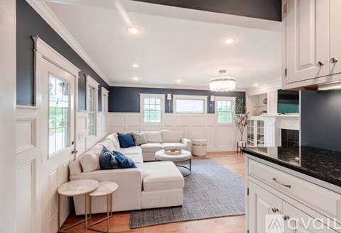 A modern living room with a white sofa and a grey rug.