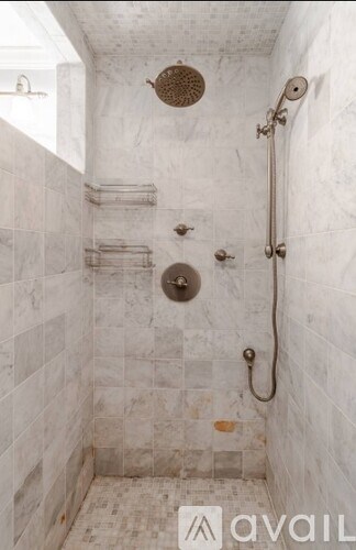 A shower with a white tile wall and floor.