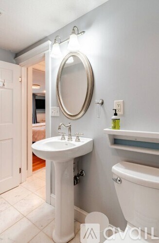 A white bathroom sink with a round mirror above it.