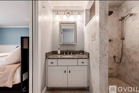 A bathroom with a marble countertop and a large mirror.