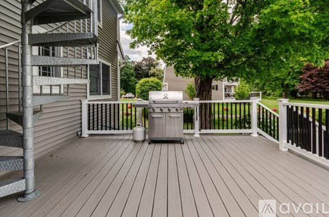 A deck with a trash can and a tree in the background.