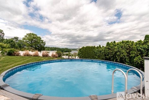 A large outdoor swimming pool surrounded by a grassy area and trees.