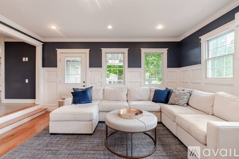 A living room with white furniture and a large window.