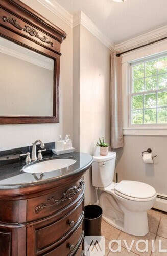 A bathroom with a toilet, sink, and mirror.