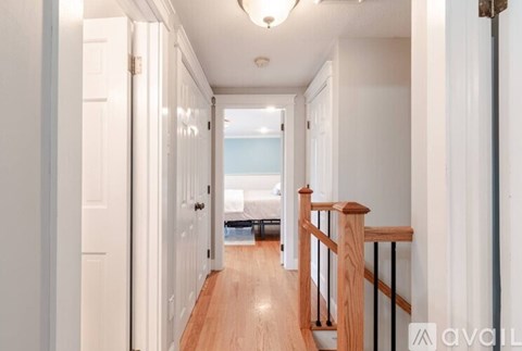 A hallway with a wooden floor and white walls.