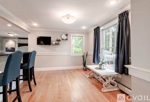 A living room with a television, two chairs, and a table with a vase of flowers on it.