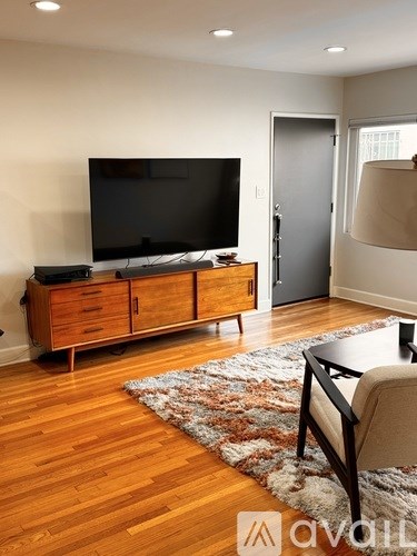 A living room with a television and a rug on the floor.