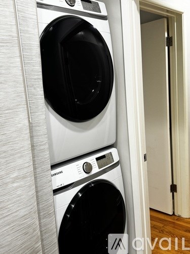 A white Samsung washing machine and dryer stacked on top of each other in a small room.
