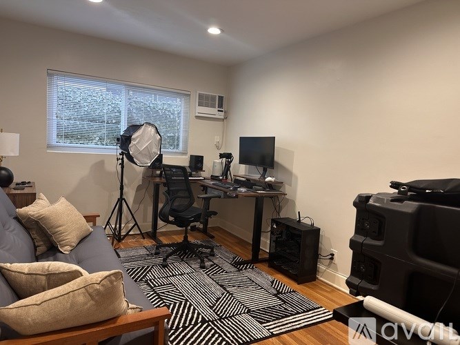 A room with a desk, a chair, a computer, and a camera light.