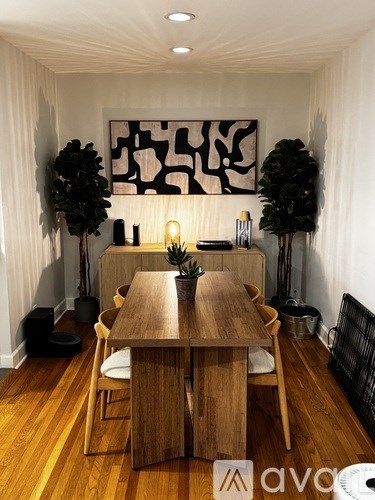 A wooden dining table with chairs and a potted plant in the middle.