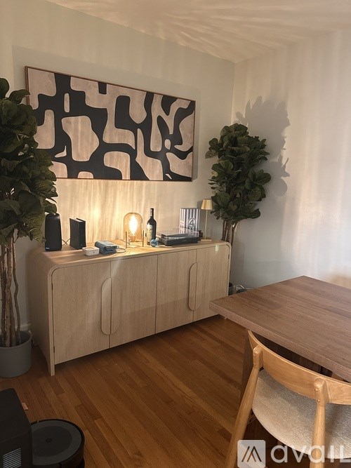A modern living room with a wooden cabinet, a table, and a potted plant.
