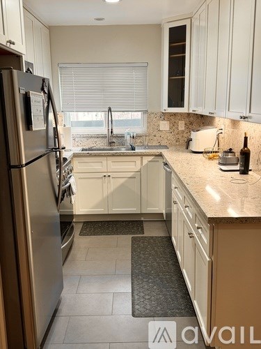 A kitchen with a refrigerator, sink, and cabinets.