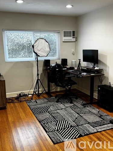 A room with a desk, chair, and a large window with a view of trees.